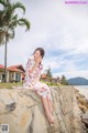 A woman in a white dress sitting on a stone wall.