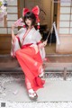 A woman in a red and white kimono sitting on a bench.