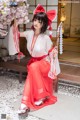 A woman in a red and white kimono sitting on a bench.