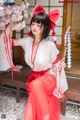 A woman in a red and white kimono sitting on a bench.