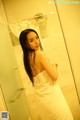 A woman in a white towel standing in a bathroom.