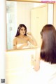 A woman brushing her teeth in front of a mirror.