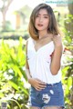 A woman in a white tank top and denim shorts posing for a picture.