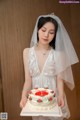 A woman in a wedding dress holding a cake.