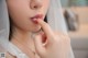 A woman in a wedding dress putting on lipstick.