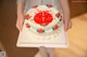 A woman holding a white cake with red and green decorations.