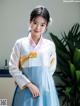 A woman in a blue and white hanbok poses for a picture.