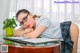 A woman wearing glasses leaning on a desk.