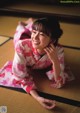 A woman in a pink kimono laying on the floor.