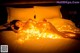 A woman laying on a bed covered in lights.