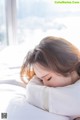 A woman laying on a bed with her head on a pillow.