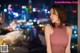 A woman standing in front of a city at night.