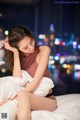 A woman sitting on top of a bed next to a window.