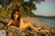 A woman in a yellow bikini laying on the beach.