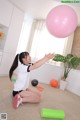 A young girl sitting on the floor playing with a pink ball.