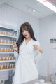 a woman in a white lab coat standing in front of a counter