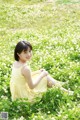 A woman in a yellow dress sitting in a field of flowers.