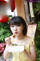 A woman in a yellow dress holding a plate of food.