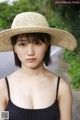 A woman in a straw hat is posing for a picture.