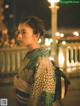 A woman in a kimono standing on a bridge at night.