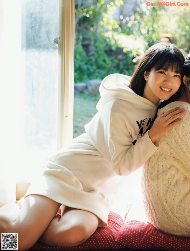 A couple of women sitting on top of a red pillow.
