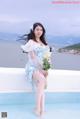 A woman sitting on the edge of a swimming pool holding a bouquet of flowers.