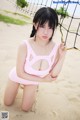 A woman in a pink bathing suit posing on a beach.