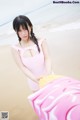 A woman in a pink bathing suit standing on a beach.