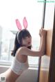 A woman wearing bunny ears leaning against a window.