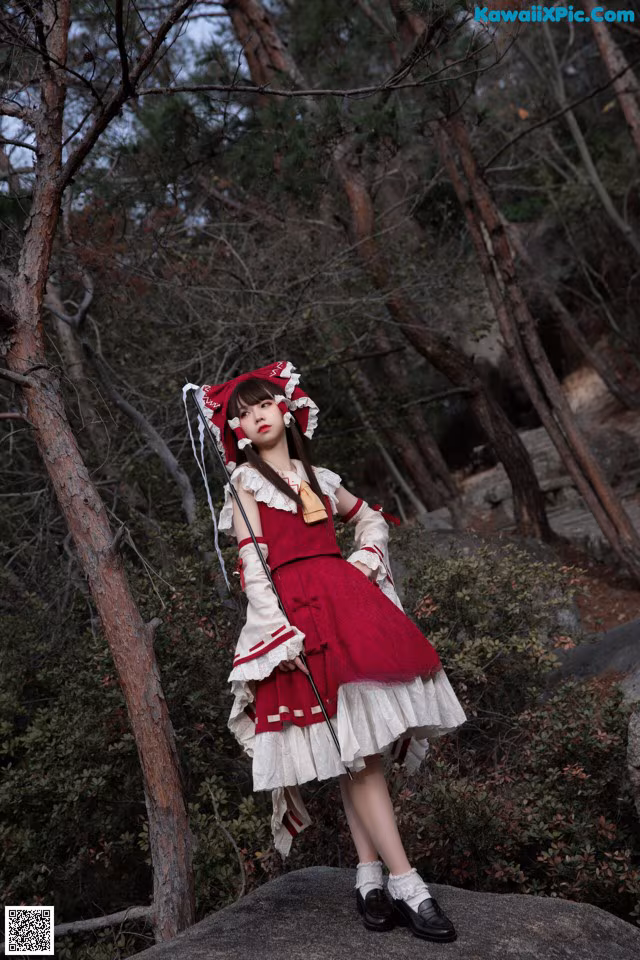 A woman in a red and white dress standing on a rock.