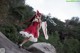 A woman in a red and white dress standing on a rock.