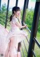 A woman in a pink dress standing on a balcony.