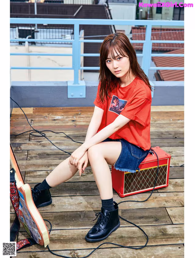 A woman sitting on top of a wooden floor next to a guitar.