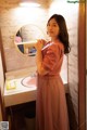 A woman standing in front of a mirror in a bathroom.