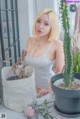 a woman sitting at a table next to a potted plant