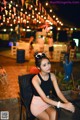 A woman sitting at a table in a restaurant at night.