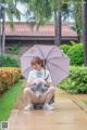 A woman sitting on the ground holding an umbrella.