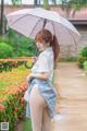 A woman in a school uniform holding an umbrella.