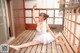 A woman in a white dress is sitting on a wooden deck.