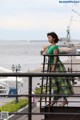 A woman in a green top and plaid skirt standing on a railing.