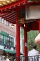 A woman taking a picture of a red archway with chinese writing.