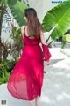 A woman in a red dress is walking down a sidewalk.